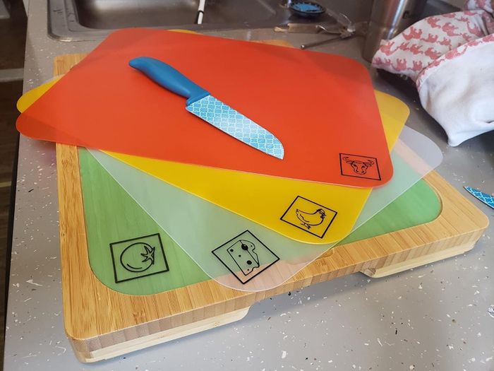 A reviewer shows the bamboo cutting board with the cutting mats for beef, chicken, cheese, and fruit neatly arranged.