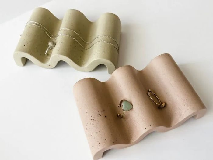 Two wavy jewelry trays, one holding a necklace and the other with earrings, showing an elegant way to organize your accessories.