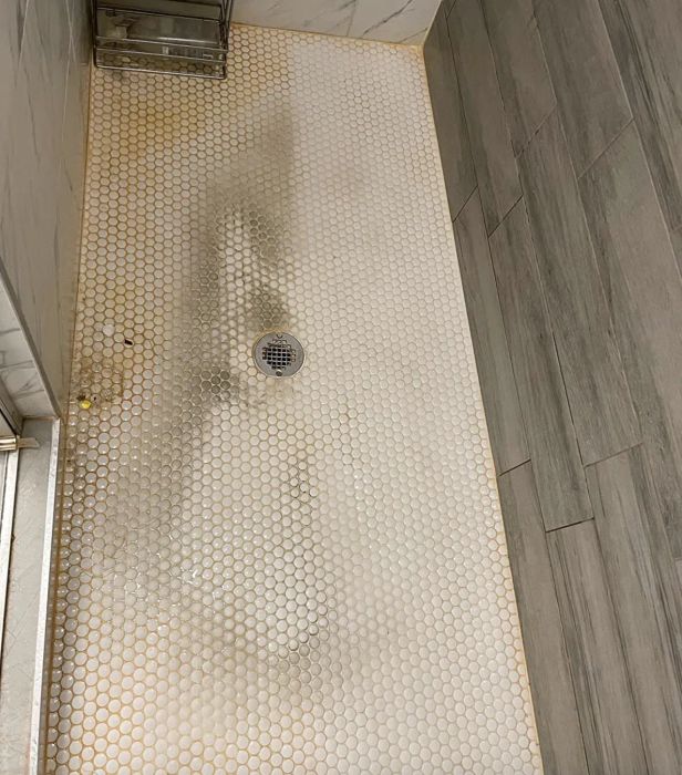 A customer review photo showing half of their shower floor cleaned with the natural cleaner, revealing its effectiveness.