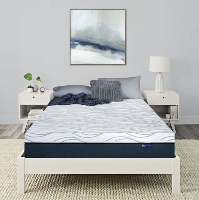 The mattress resting on a bed with sheets and pillows