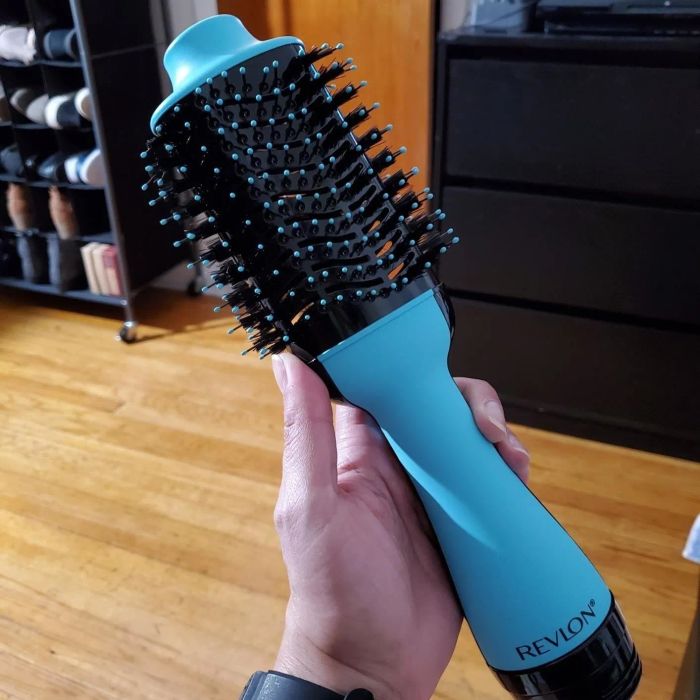 A hand holding a round brush with bristles all around it