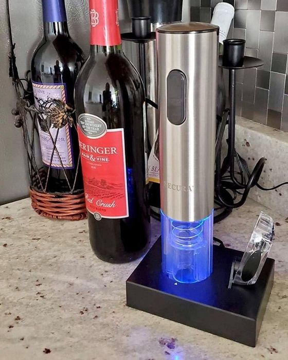 A reviewer's photo showing the electric wine opener resting on its illuminated charging dock.