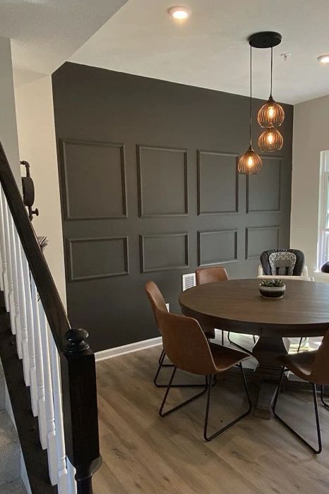 A reviewer displaying the panels painted on a bold black wall, showcasing the stylish effect they create.