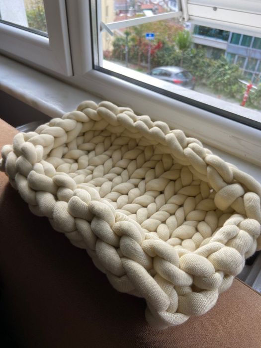 A close-up shot of the cream-colored cat bed.