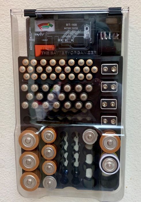A reviewer shows a photo of the organizer filled with various types of batteries.