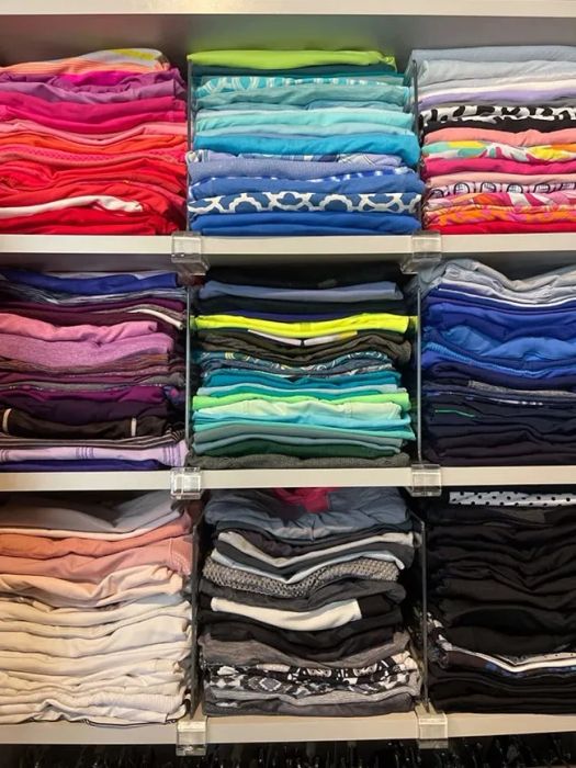 A photo showing the clear shelf dividers in use, neatly separating various t-shirts.