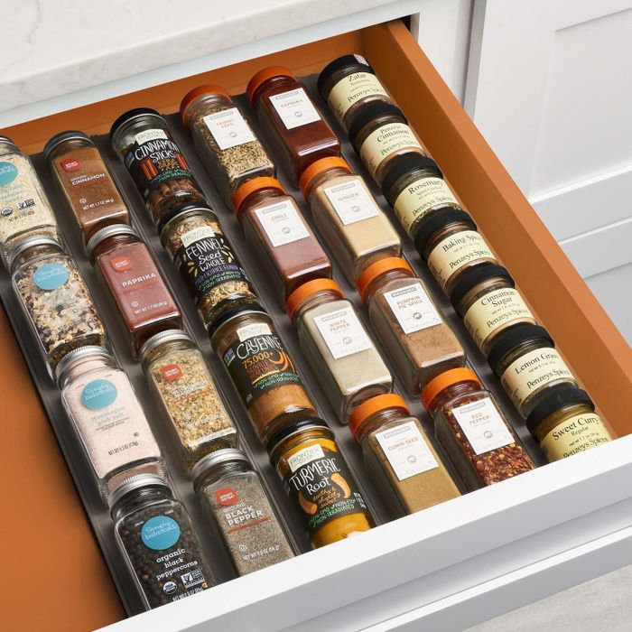 The same drawer now organized with spice bottles neatly arranged, labels facing up in the organizer.