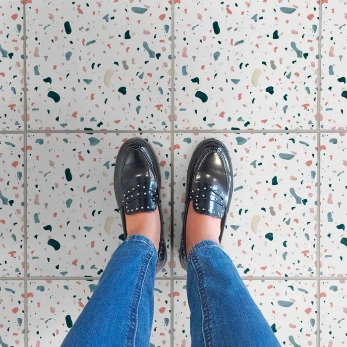 A person standing on a terrazzo-tiled floor, enjoying the vibrant design.