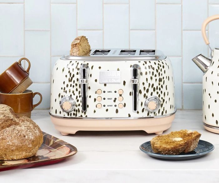 A four-slice toaster with two dials, six buttons, and a charming black spotted pattern.
