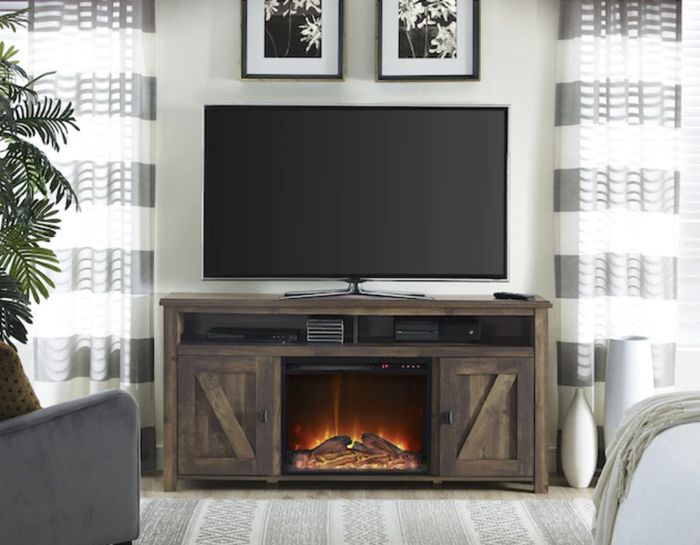 The charming rustic entertainment center, complete with a TV on top and a glowing fireplace underneath