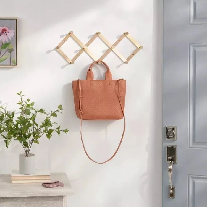 A leather tote bag hanging on a wooden rack by the door, combining style and practicality for a chic storage solution.