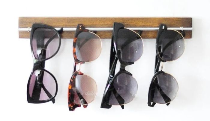 The sunglass organizer mounted on a wall, holding a full collection of sunglasses.