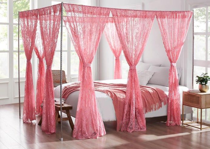 A canopy bed adorned with sheer, delicate lace curtains, positioned in a bright and airy bedroom setting.