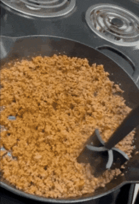 gif of a reviewer using the masher to break up ground meat being browned in a skillet