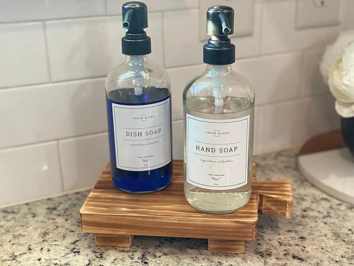 A reviewer’s hand and dish soap placed on a wooden pedestal