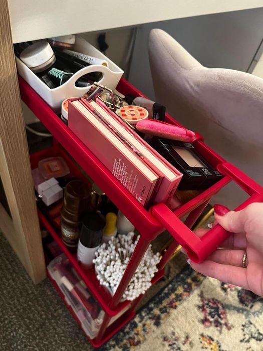 A red rolling cart filled with a variety of beauty products.