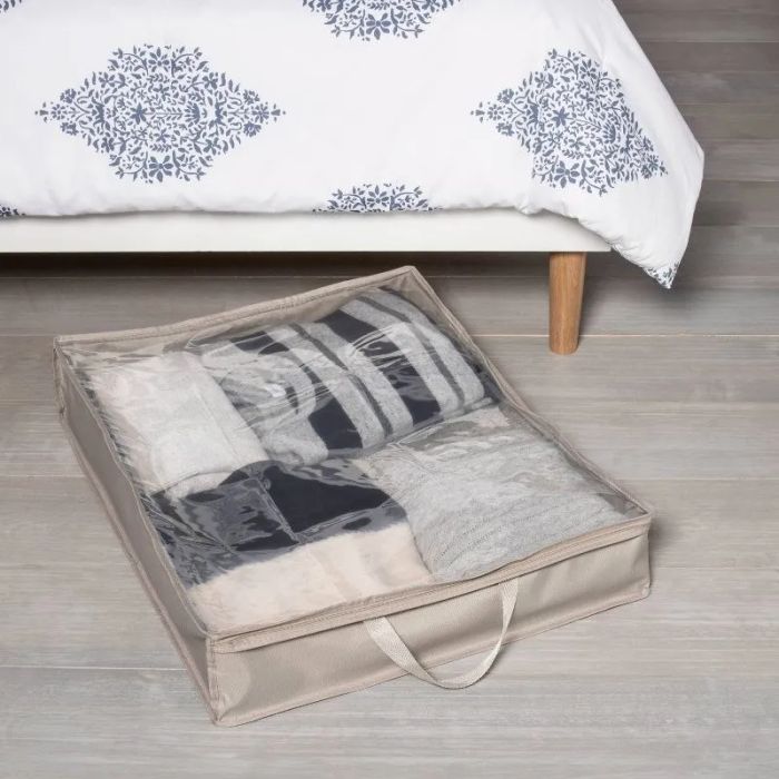 Clear storage bin holding a stack of folded blankets next to the bed, ideal for organizing extra linens.