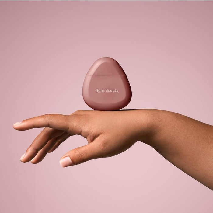 A triangular-shaped hand cream resting on top of a model’s hand