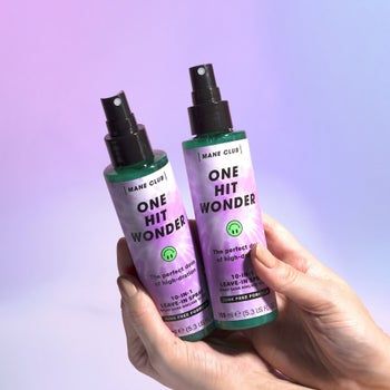 Model holding two bottles of Mane Club NYC One Hit Wonder spray