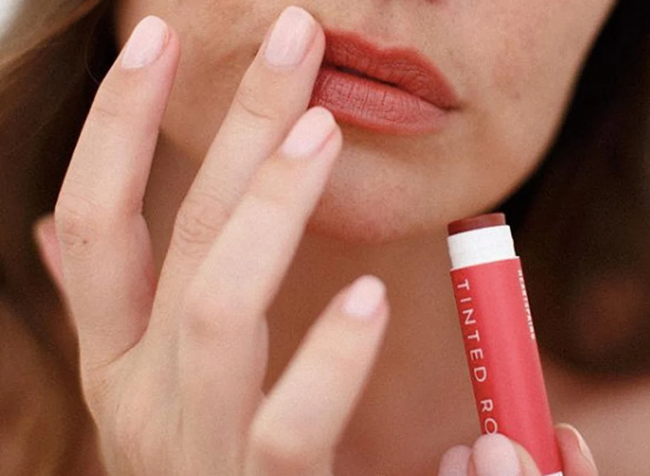 Person applying tinted lip balm to their lips