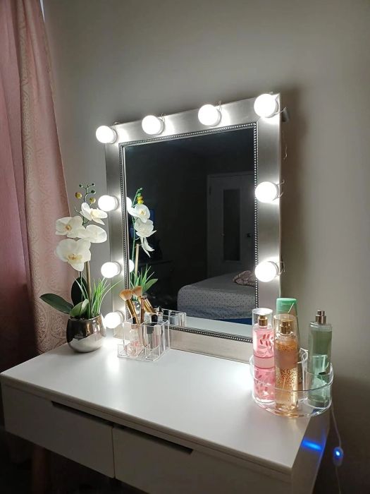 Another reviewer's vanity table featuring a lit mirror, orchids, and an assortment of beauty products arranged neatly.