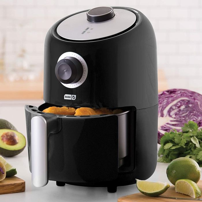 A black air fryer featuring an analog timer, a round temperature dial, and a handy handle for easily removing the basket.