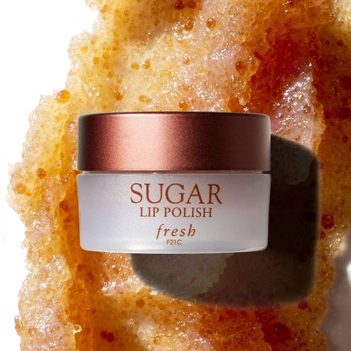 A container of Fresh Sugar Lip Polish placed on a textured swatch