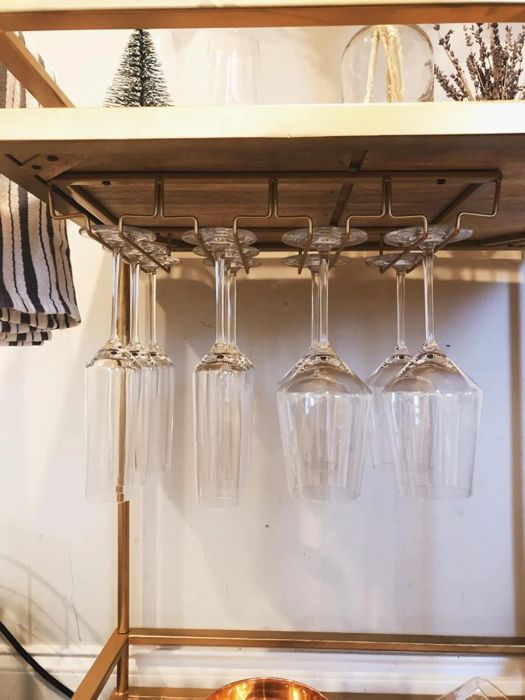 Another reviewer's gold stemware holder mounted beneath a bar cart, holding an assortment of glasses.