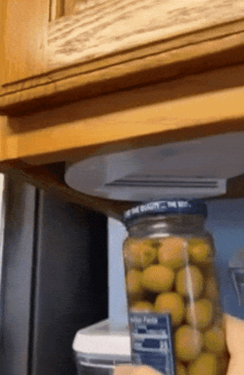 A gif of a reviewer effortlessly opening a jar of olives with just one hand using the lid opener
