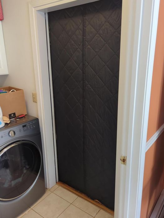A black insulated door curtain hanging over a reviewer’s laundry room door