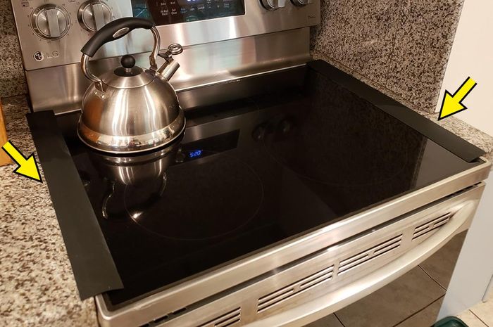 reviewer image of black gap covers placed on either side of the stove