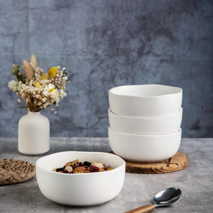 Four white stackable bowls with uneven edges