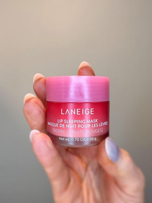 A person holding a jar of Laneige Lip Sleeping Mask in berry flavor, showcasing its small size perfect for skincare routines.