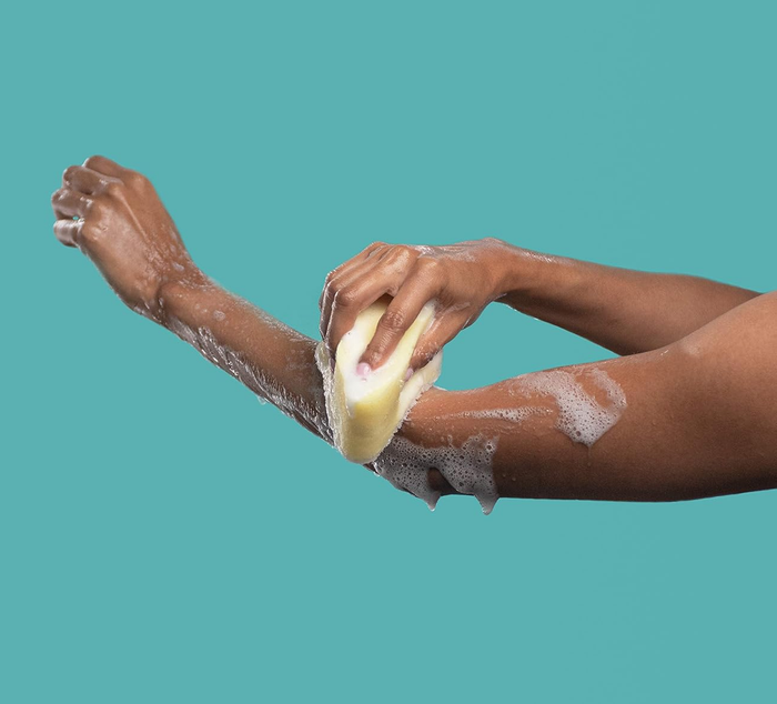 Person using a soap-filled sponge to lather their arm