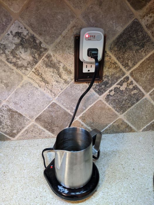 A reviewer's mug warmer plugged into the auto shutoff outlet