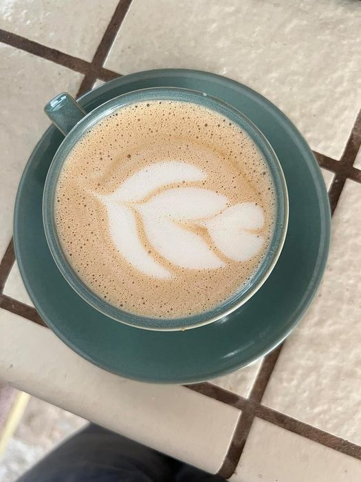 A cappuccino with beautiful latte art resting on a tiled table, featured in a shopping guide.