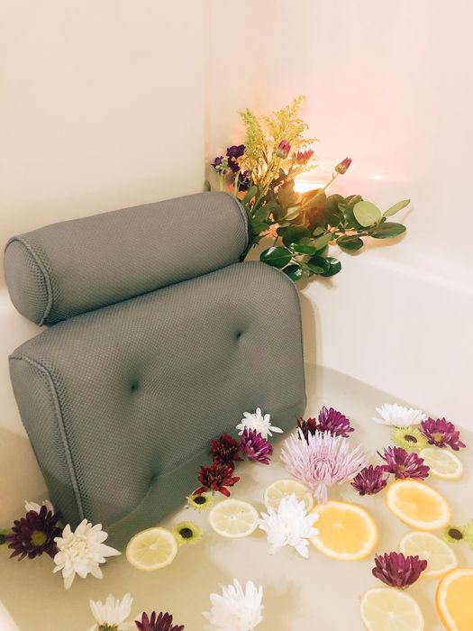 Imagine a bathtub adorned with a plush bath pillow, floating flowers, fresh lemon slices, and a touch of greenery, creating the perfect spa-like atmosphere.