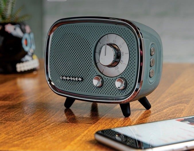 A Crosley Bluetooth retro-style speaker on a wooden table, promoting seamless digital music streaming in style.