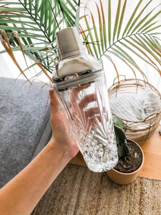 A reviewer holds the sleek clear and stainless steel cocktail shaker.