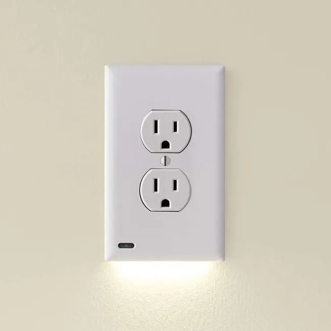 A close-up view of the outlet cover plate with its LED light glowing softly.