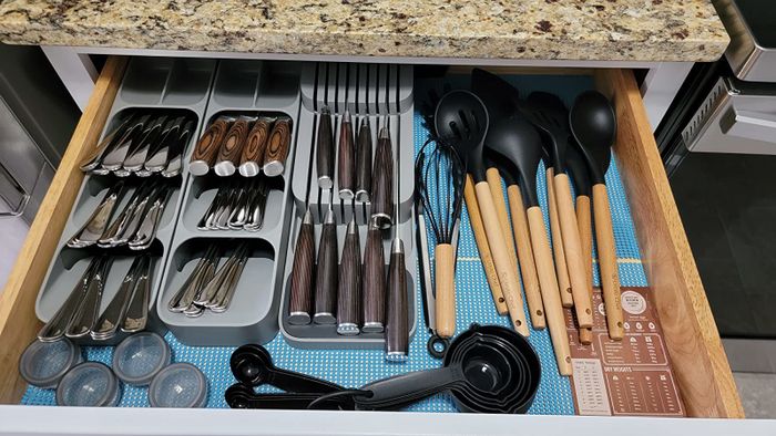 A reviewer shows an organized kitchen drawer featuring three gray silverware sorters.