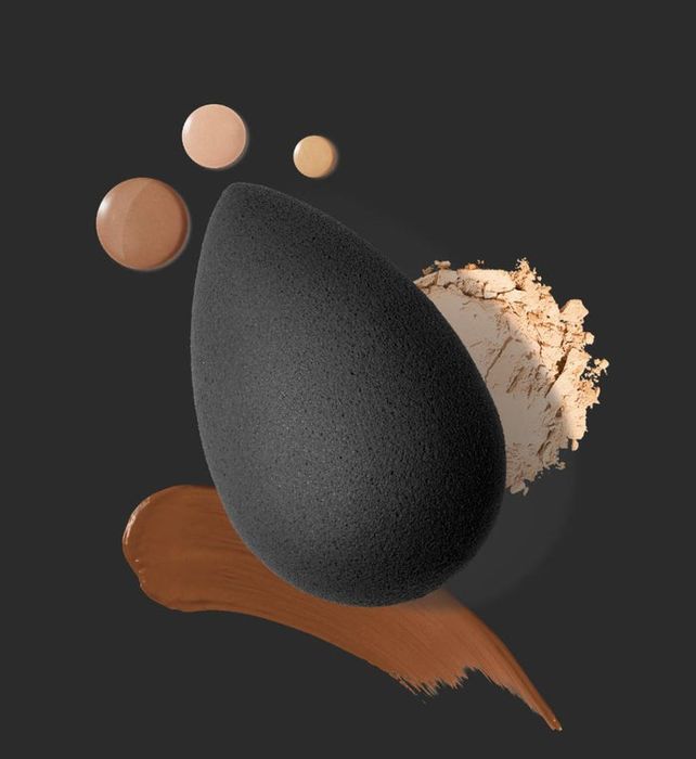 Black makeup sponge alongside swatches of foundation and powder