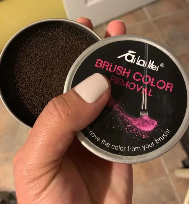 A reviewer holding a tin with the dry sponge inside