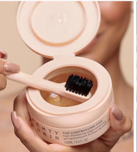 An open jar of Fenty Beauty Hair Gel with a toothbrush-style applicator