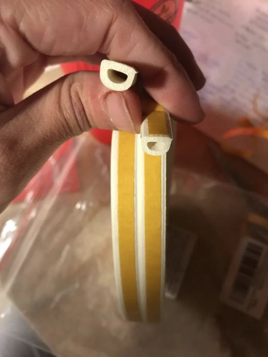 A reviewer taking a close-up shot of the insulation material on the soundproofing strip.