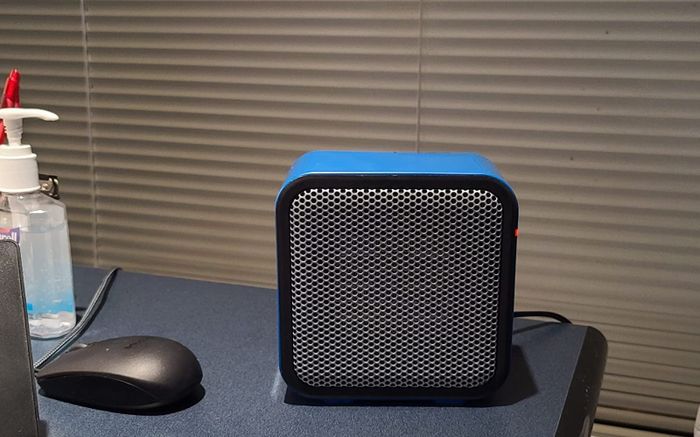 A reviewer’s photo of the compact blue heater placed on the corner of a desk