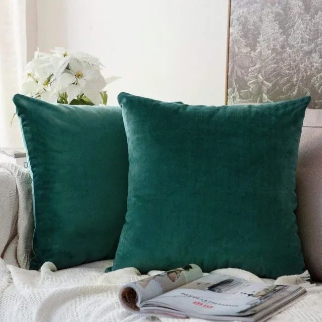 Two green velvet throw pillows resting on a couch