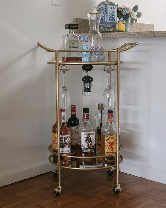 A reviewer’s bar cart placed in the corner of their dining room, filled with liquor bottles and various barware, exuding an elegant ambiance.