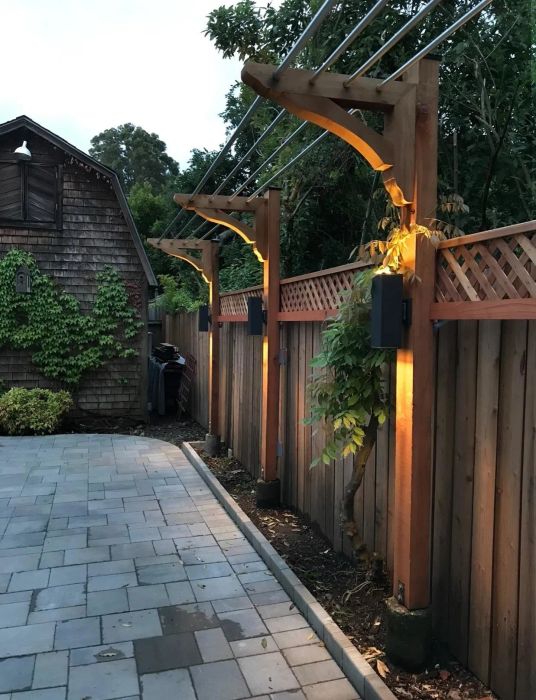A reviewer’s image showcasing three outdoor lights hung on fence posts.