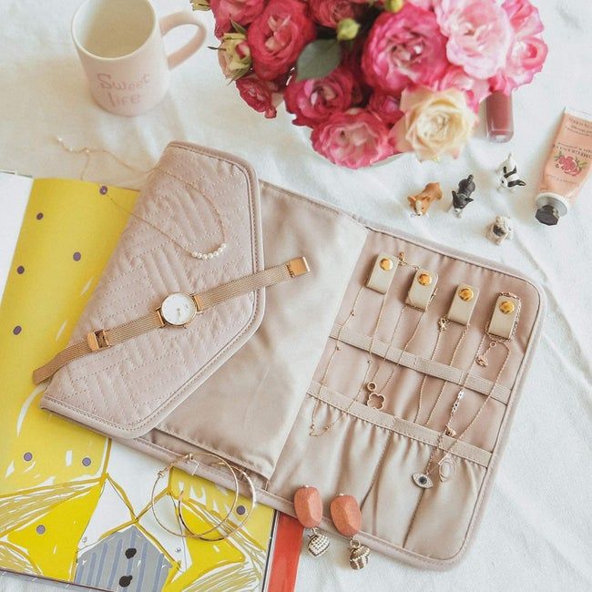 The light pink fabric organizer laid flat, with various pieces of jewelry neatly stored inside.